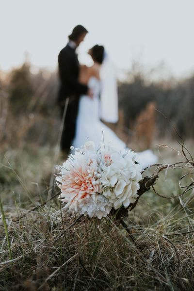 a newely wedded couple standing in front of a bouqet of floweres